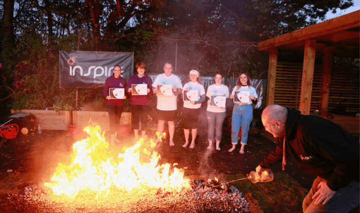 Five woman and a man holding certificates after completing the firewalk